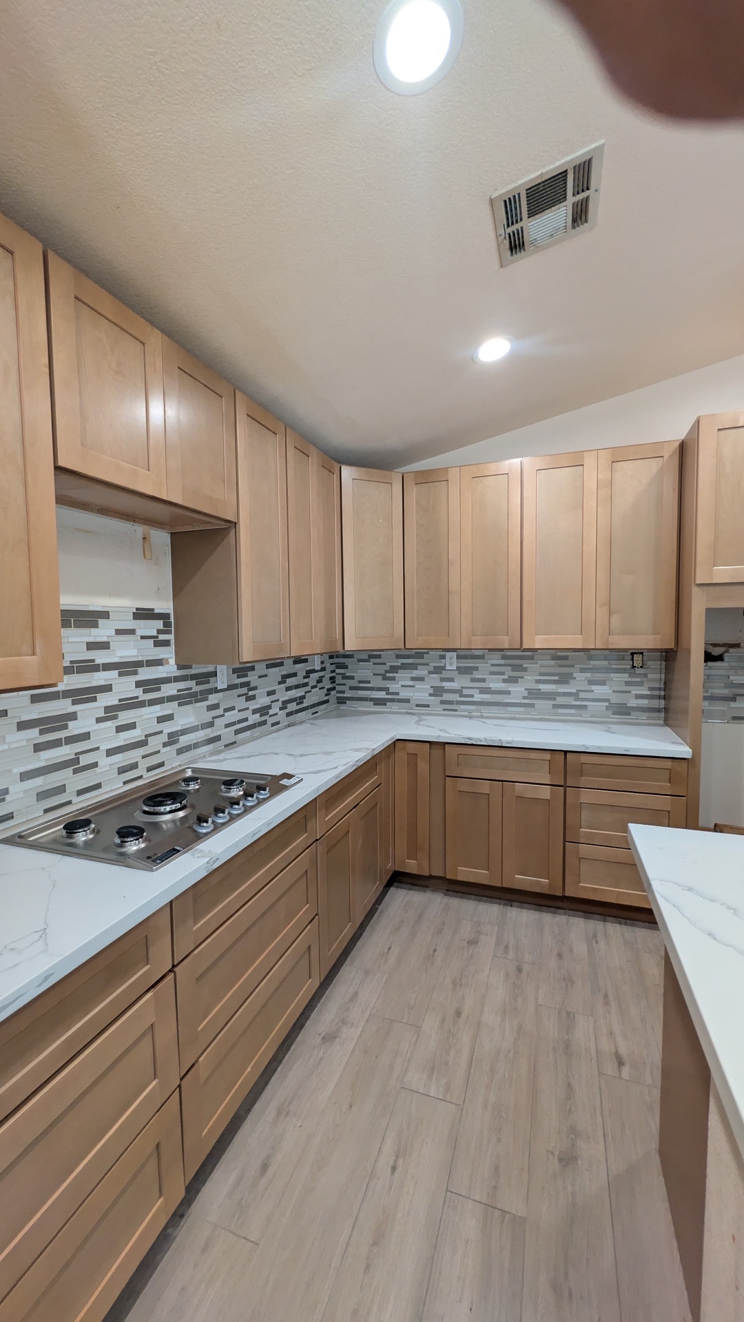 Maple shaker kitchen with stainless gas cooktop, calacatta counters and tile backsplash